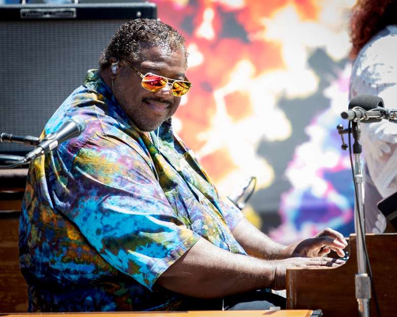 man plays piano, sunglasses on