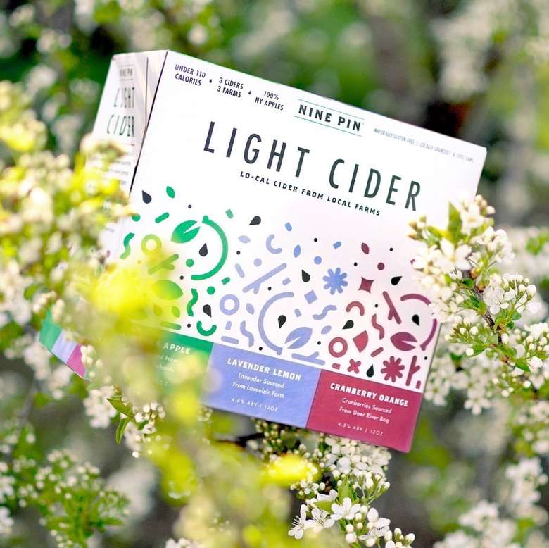 Box of Light Cider placed in a beautiful blooming bush