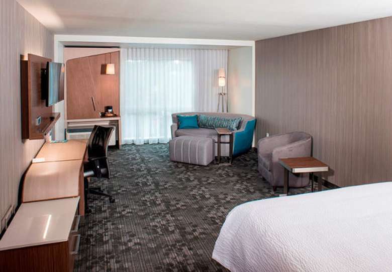 a spacious hotel bedroom with a bed on one side and a sofa couch on the other side