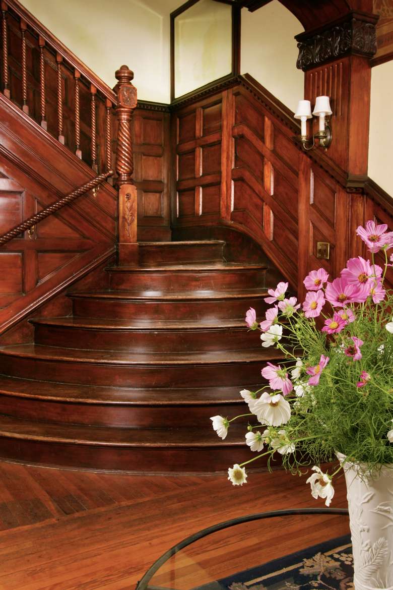 large wooden staircase with flowers on a table in front of it