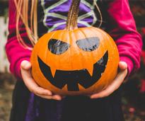 the hands of a little girl holding a painted pumpkin