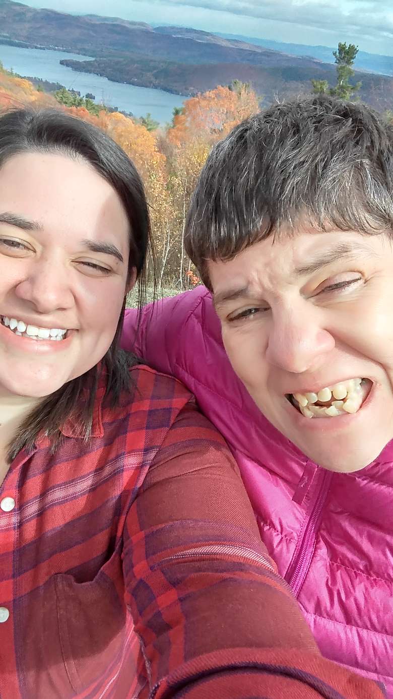 Two women smiling for the camera with a lake in the background