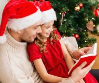 father and daughter reading book on christmas