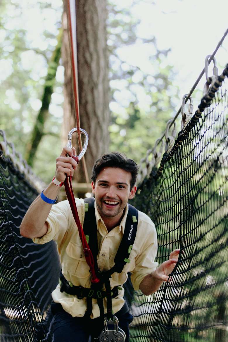a man walking across a rope bridge