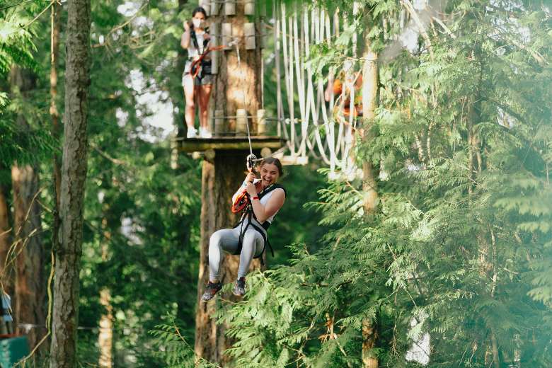 a woman ziplining across trees
