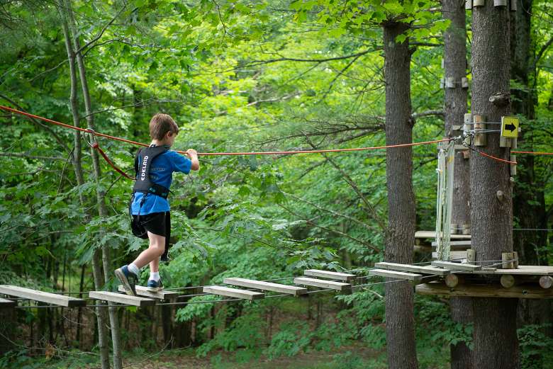 kid walking on a treetop course bridge