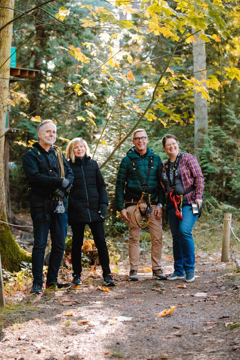 two men and two women standing by trees