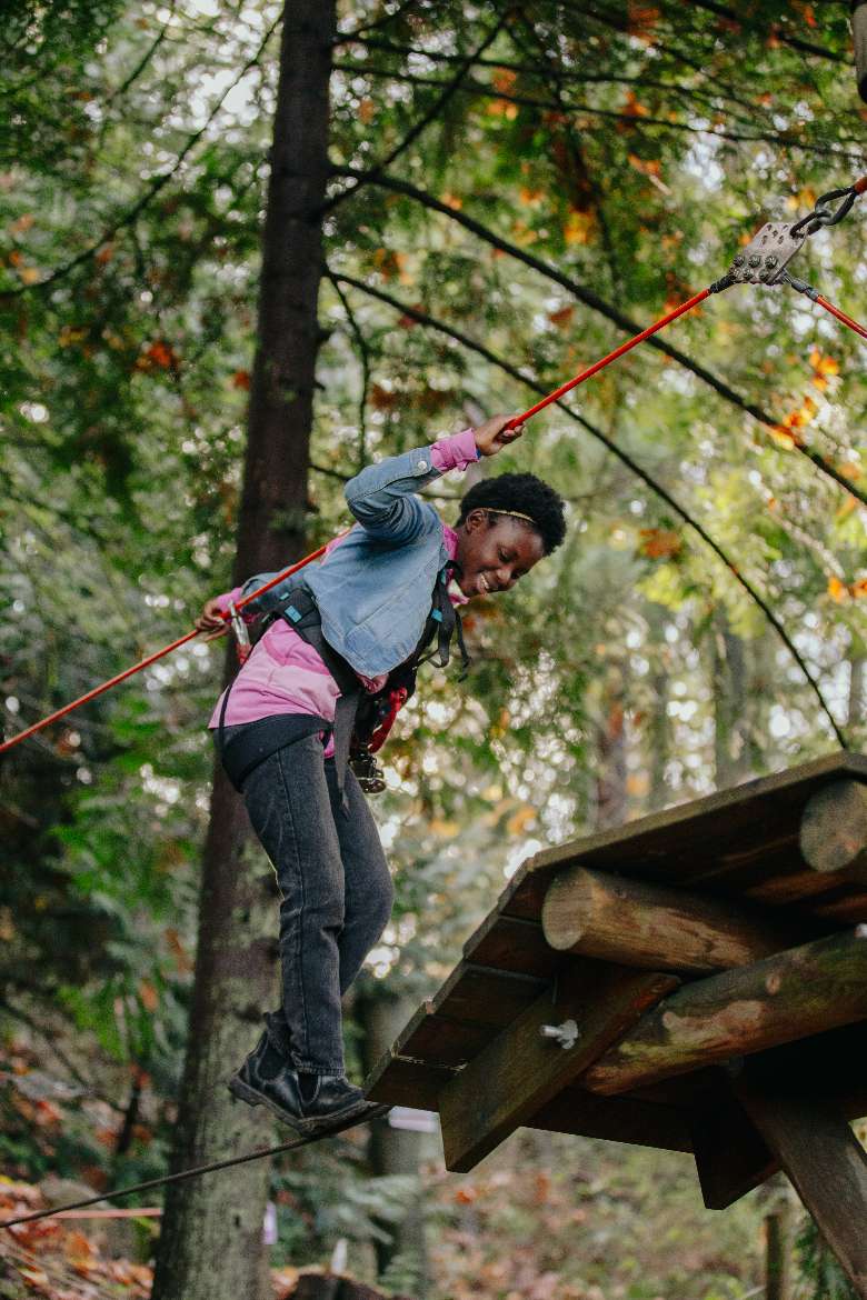 a woman walking across a tightrope in the trees