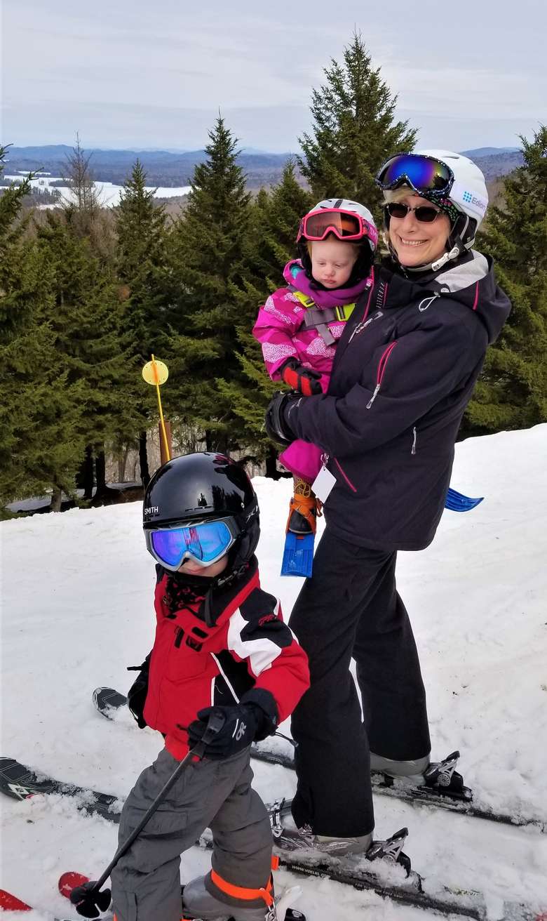 Grandma with her two grandchildren on the top of McCauley Mountain wearing skis